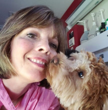 Anita L. Platt Owner Anita's Puppy Palace being kissed by a dog she just groomed